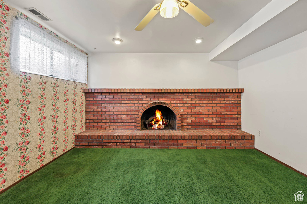 Unfurnished living room featuring carpet flooring, a fireplace, and a ceiling fan
