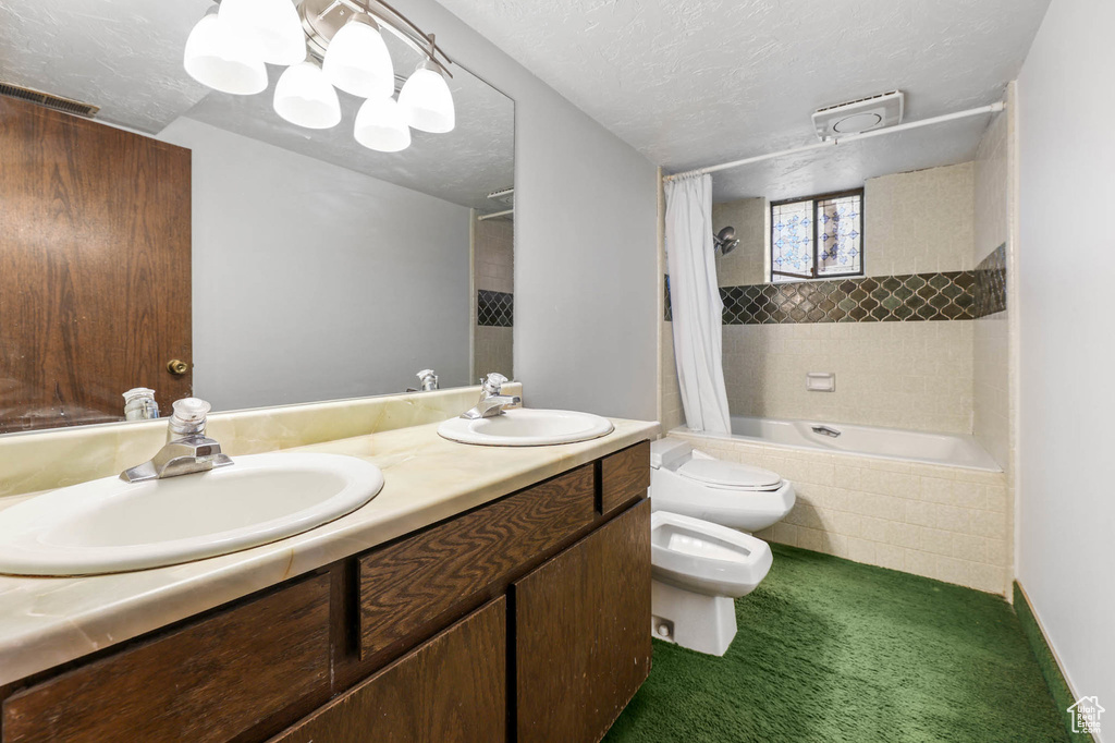 Full bathroom with tiled shower / bath, a bidet, double vanity, and a textured ceiling
