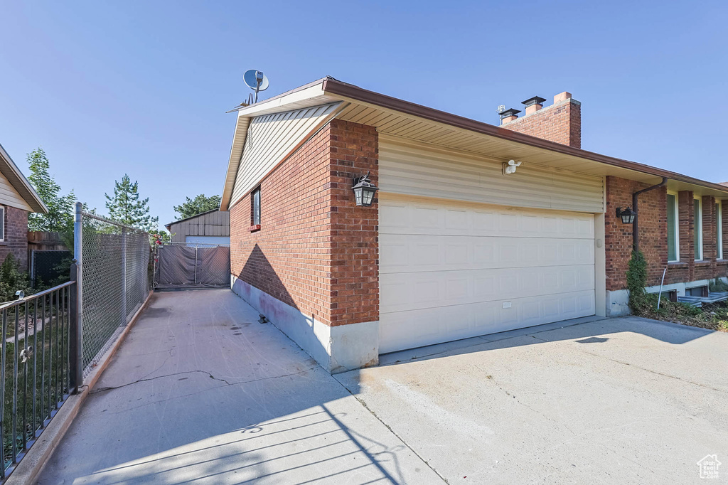 View of home\'s exterior with brick siding, a chimney, concrete driveway, and a garage