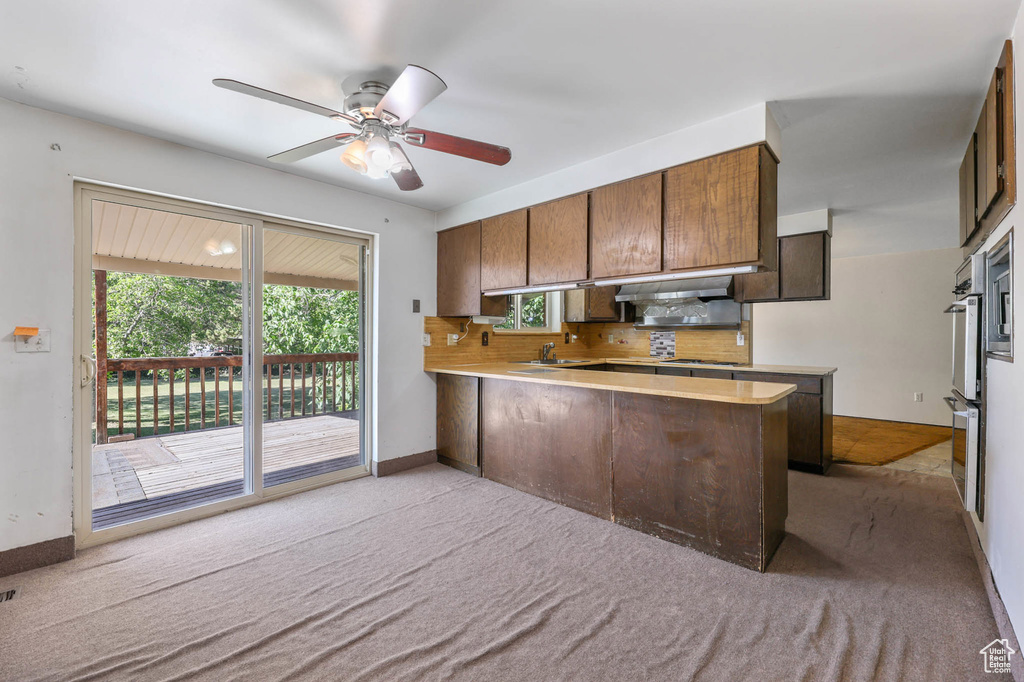 Kitchen with carpet, decorative backsplash, and a peninsula