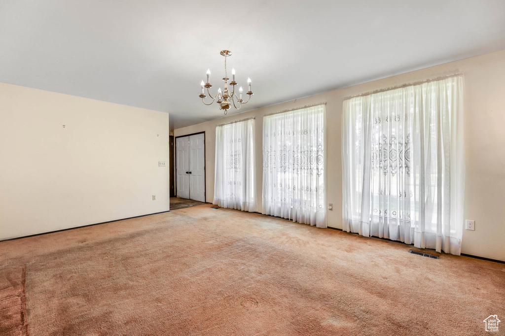 Spare room with carpet flooring and a chandelier