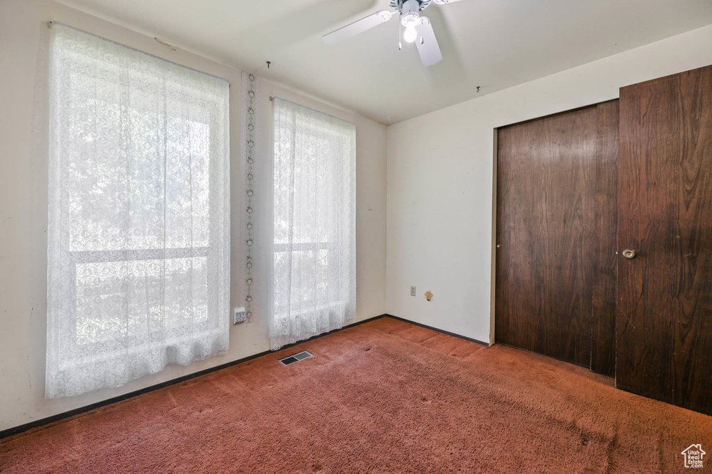 Unfurnished bedroom featuring carpet, a closet, and a ceiling fan