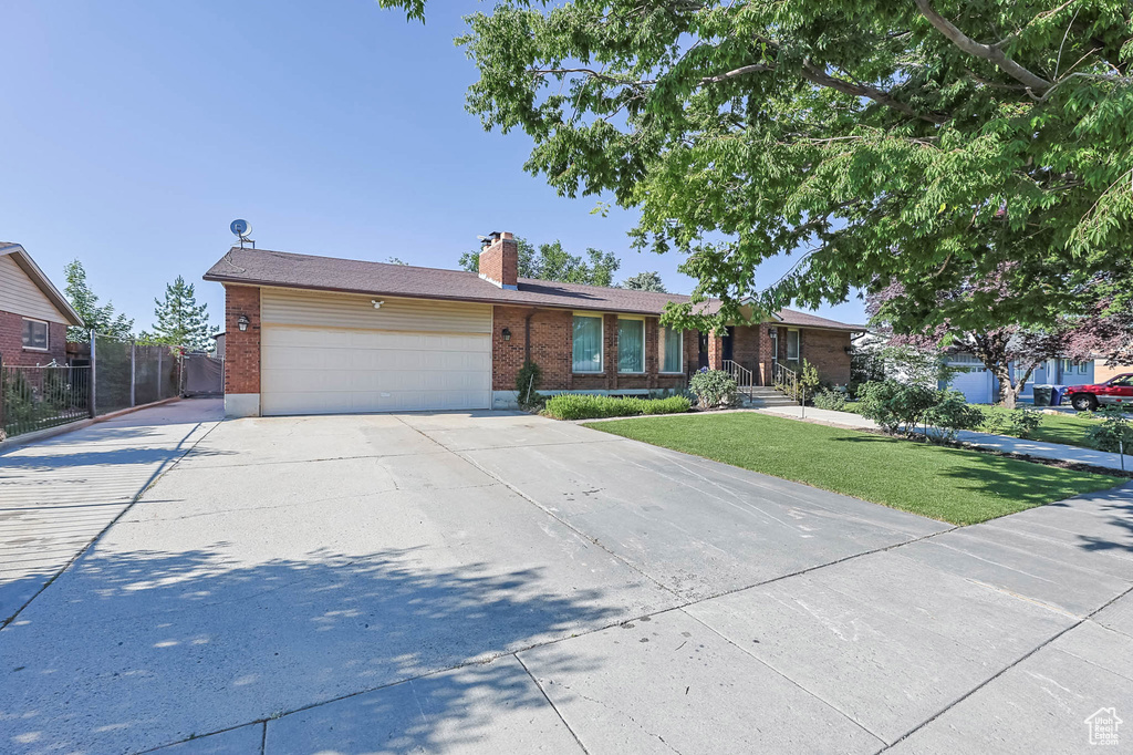 Ranch-style home with a garage, driveway, brick siding, and a chimney