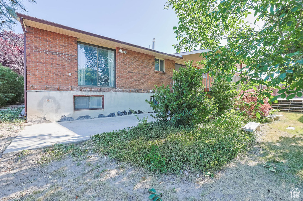 View of property exterior featuring brick siding and a patio area