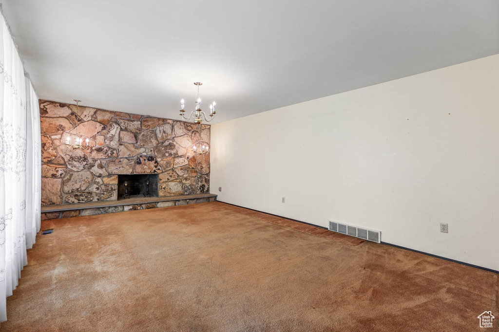 Unfurnished living room featuring carpet floors and a chandelier