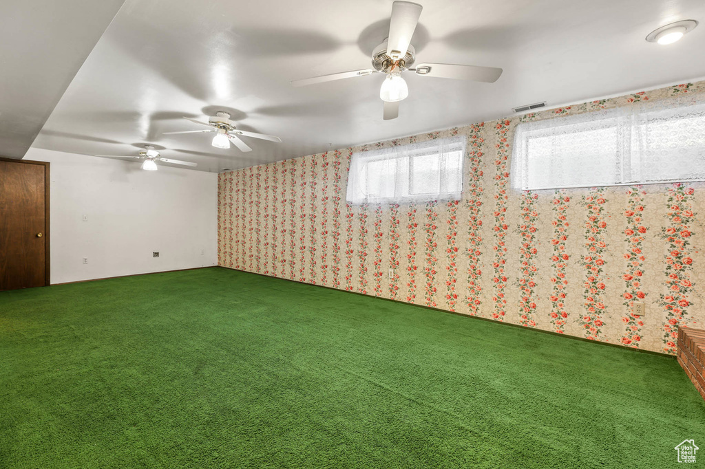 Spare room with carpet floors, wallpapered walls, and a ceiling fan