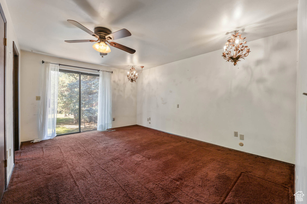 Carpeted spare room with a chandelier and a ceiling fan