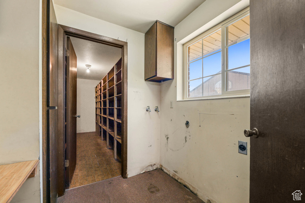 Laundry room featuring electric dryer hookup, cabinet space, and carpet