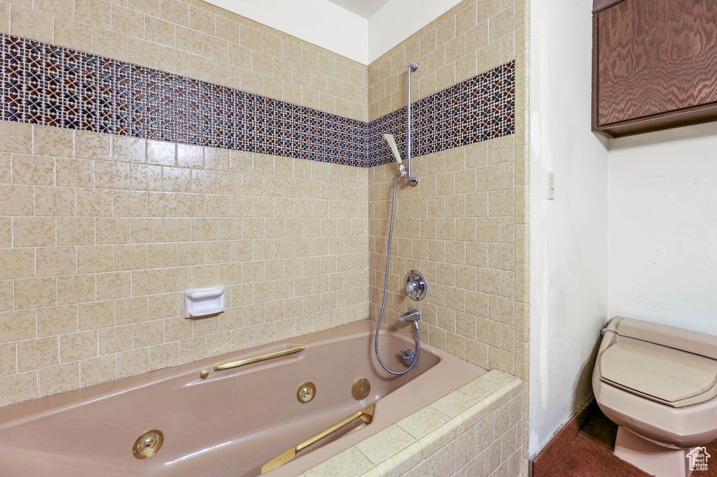 Bathroom with toilet and a combined bath / shower with jetted tub