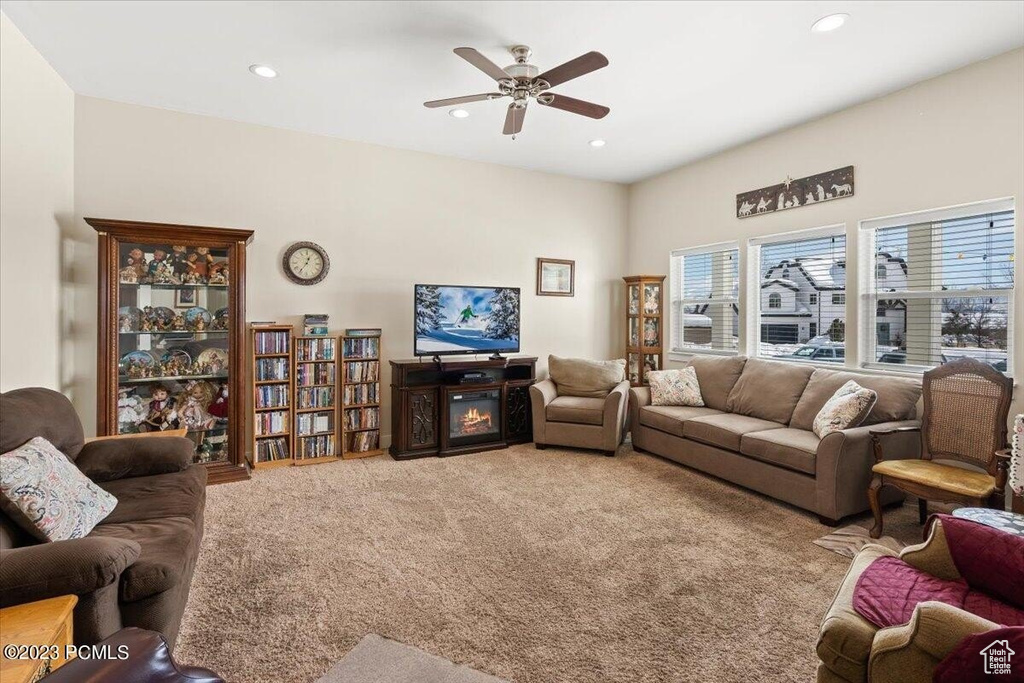 Living room with carpet, ceiling fan, recessed lighting, and a glass covered fireplace