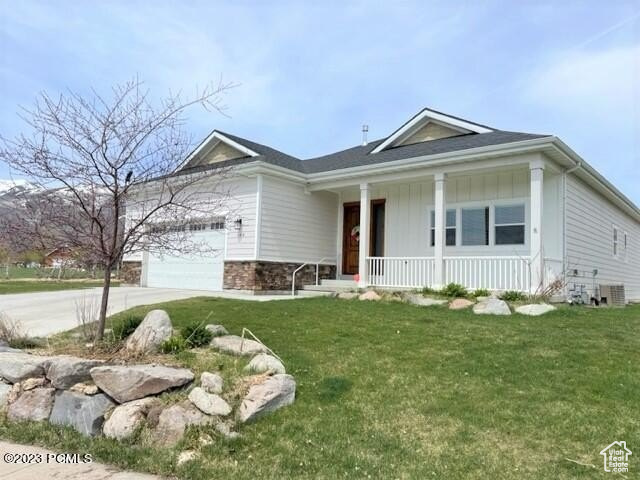 View of front of home featuring a porch, concrete driveway, an attached garage, and a front lawn