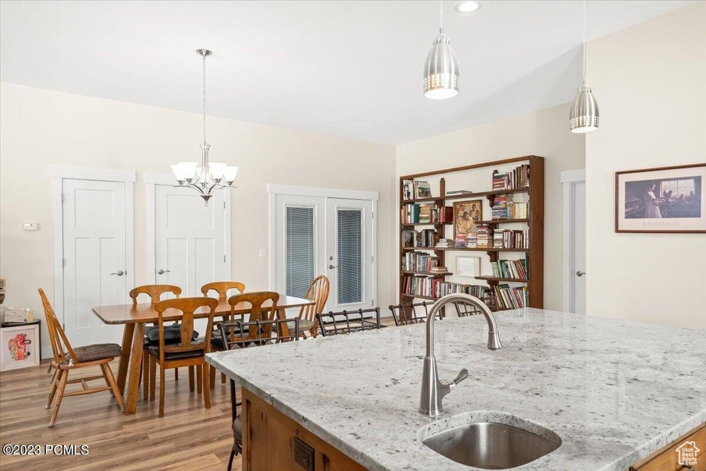 Kitchen featuring light wood-type flooring, pendant lighting, a chandelier, and light stone countertops