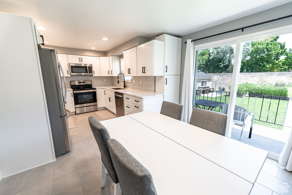Kitchen with appliances with stainless steel finishes, light countertops, backsplash, white cabinetry, and recessed lighting