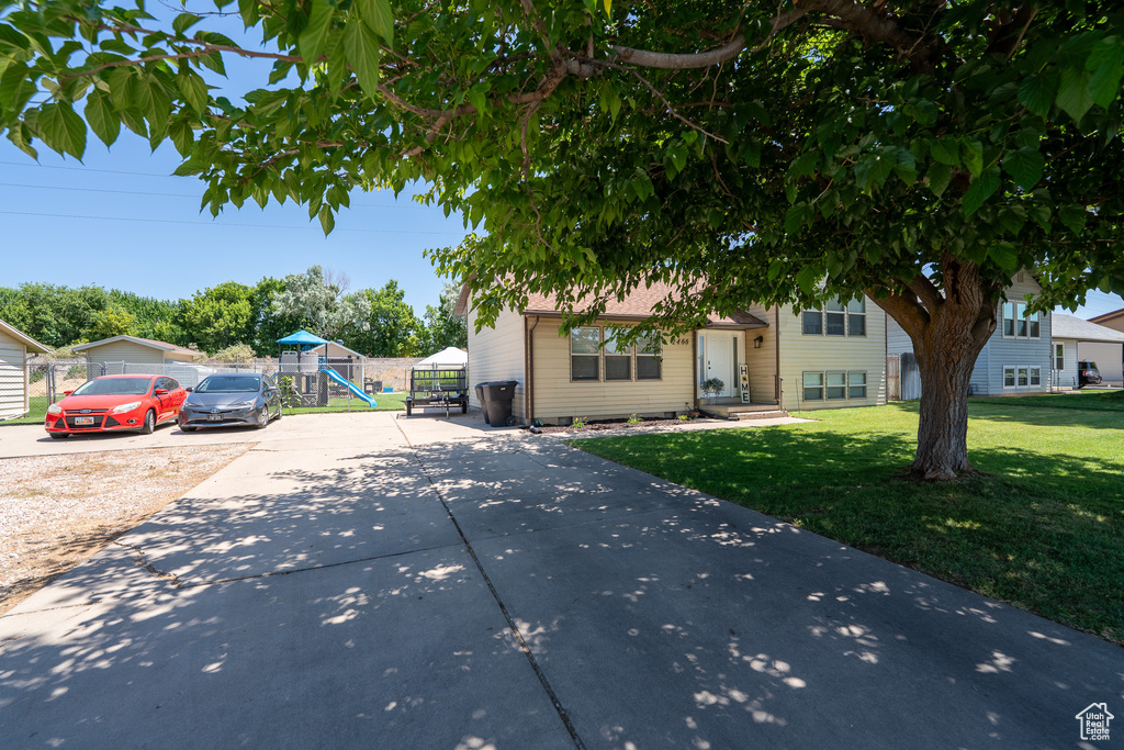 View of front of house with concrete driveway, a front lawn, and a playground