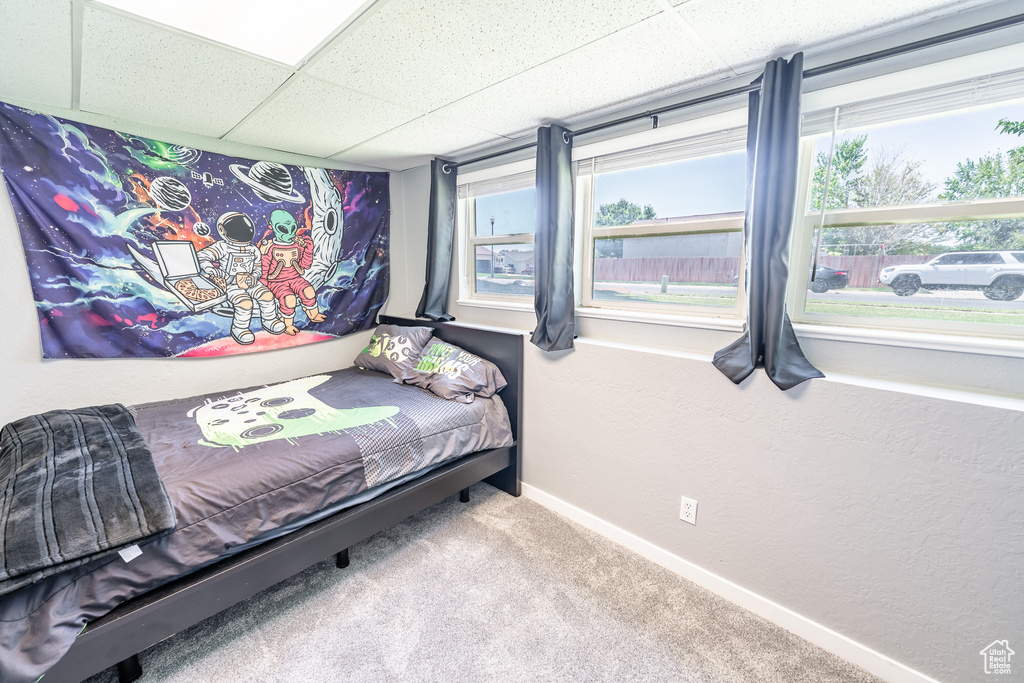Carpeted bedroom featuring a drop ceiling and baseboards
