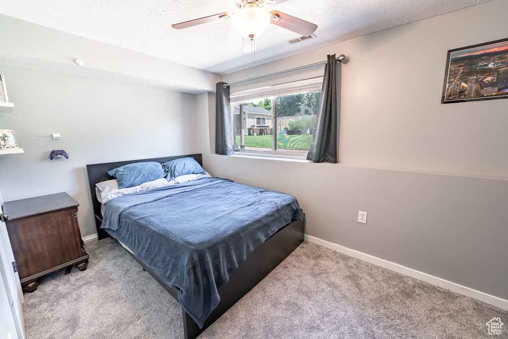 Carpeted bedroom featuring ceiling fan and a textured ceiling