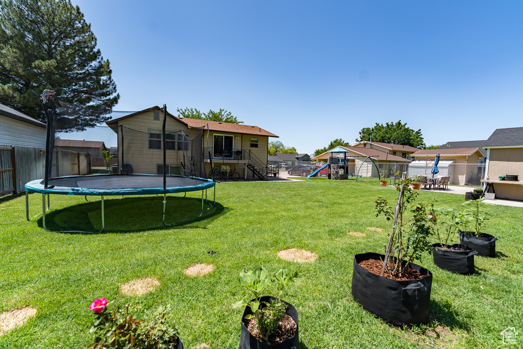 Fenced backyard with a trampoline, a playground, and stairway
