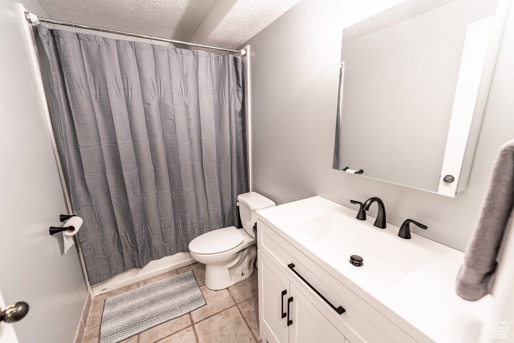 Bathroom with a textured ceiling, vanity, and tile patterned flooring