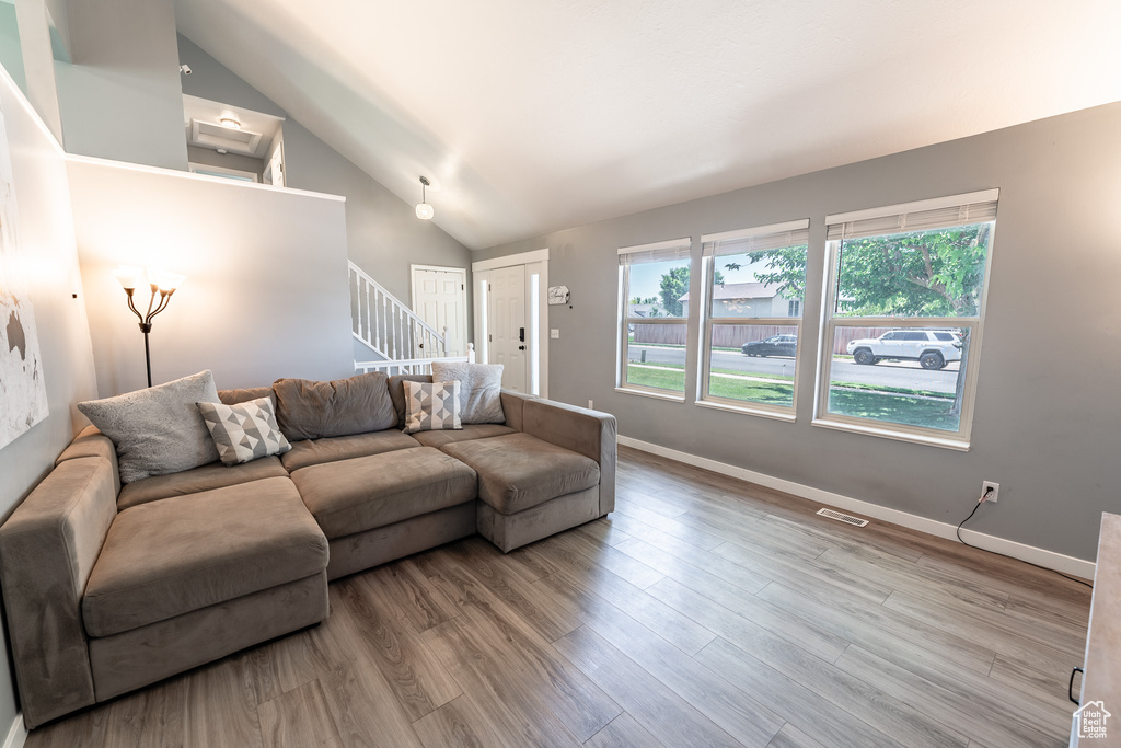 Living area featuring stairway, wood finished floors, and high vaulted ceiling