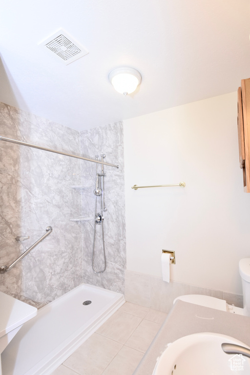 Bathroom featuring a tile shower and toilet
