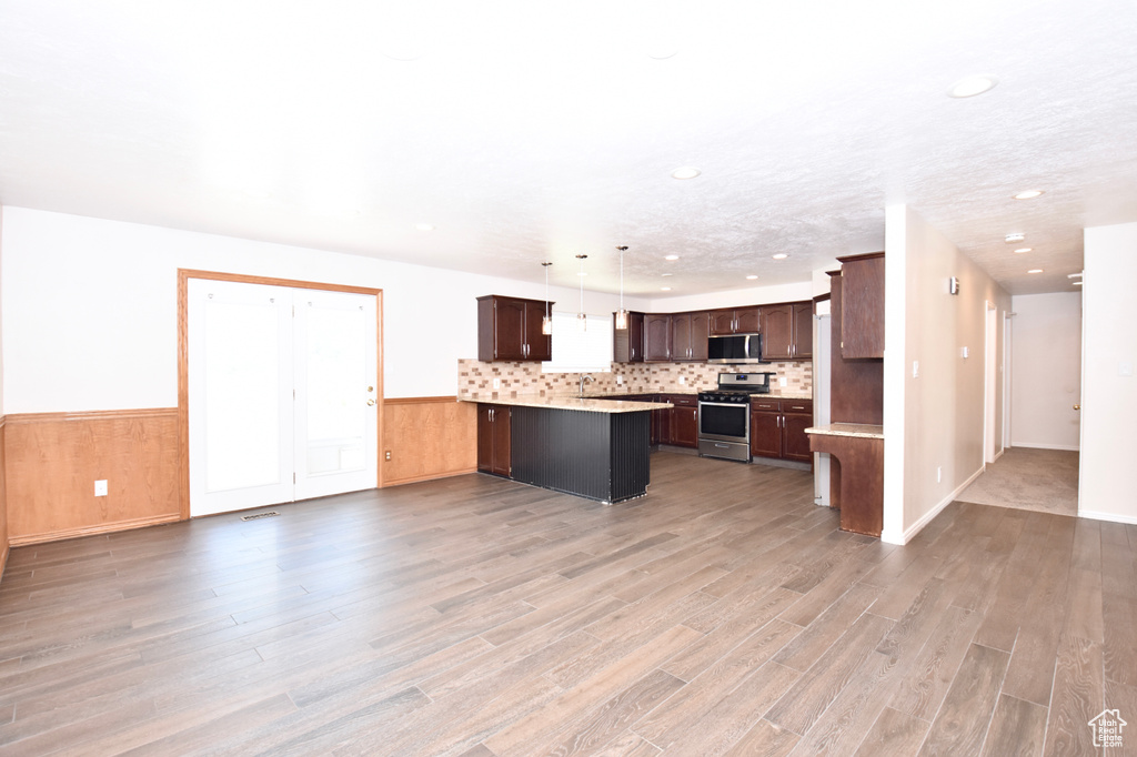 Kitchen with appliances with stainless steel finishes, a peninsula, light wood-style flooring, light countertops, and recessed lighting