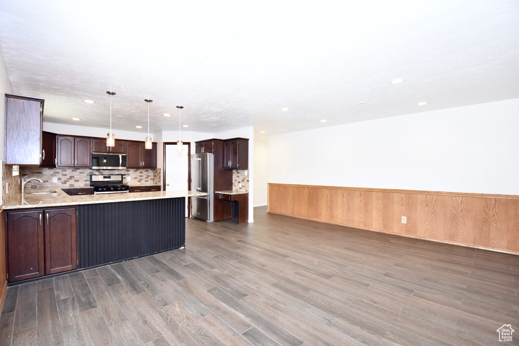 Kitchen featuring appliances with stainless steel finishes, a peninsula, light wood finished floors, dark brown cabinetry, and recessed lighting