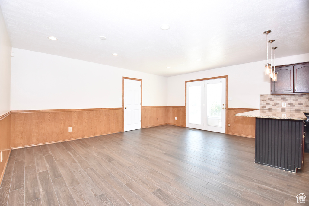 Unfurnished living room featuring a wainscoted wall, light wood-type flooring, recessed lighting, and wood walls