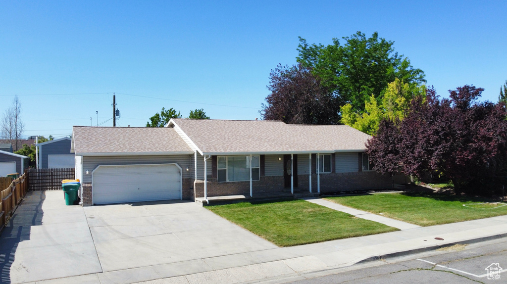 Single story home featuring an attached garage, brick siding, driveway, roof with shingles, and covered porch