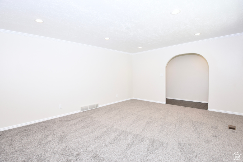 Carpeted spare room featuring recessed lighting, crown molding, and arched walkways