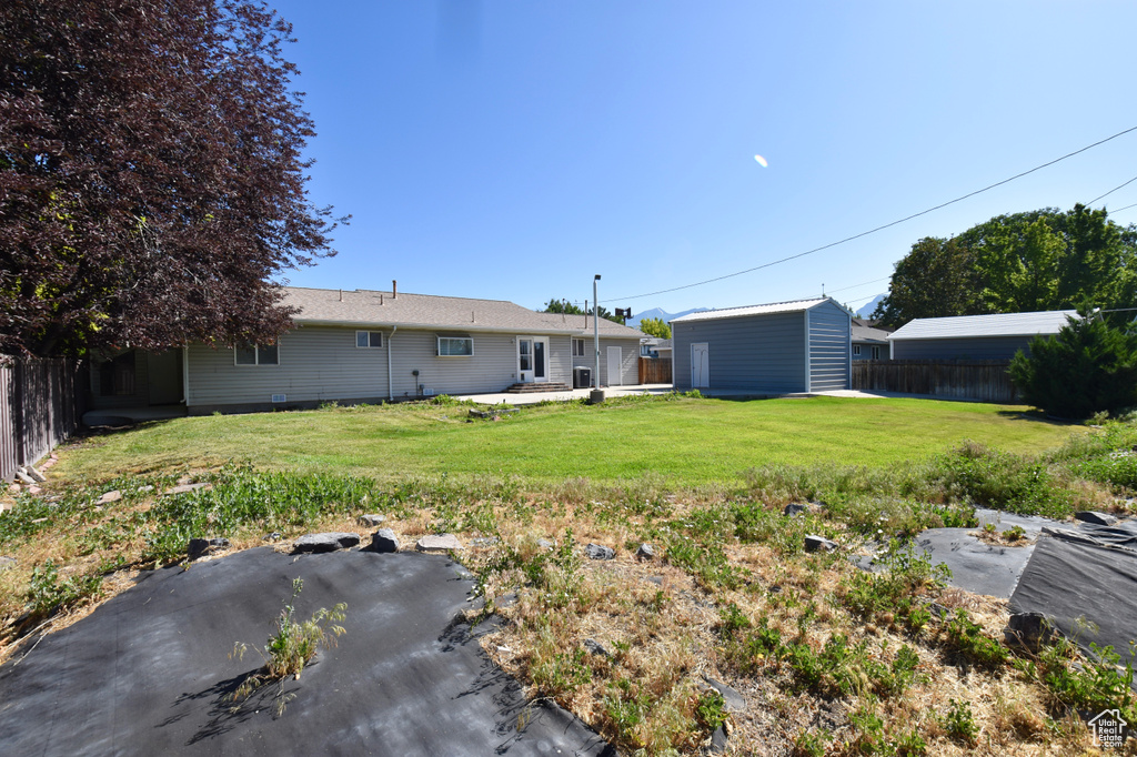Fenced backyard featuring an outbuilding and a patio