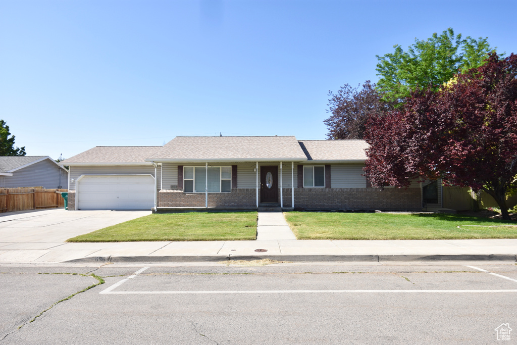 Ranch-style home featuring an attached garage, brick siding, and driveway