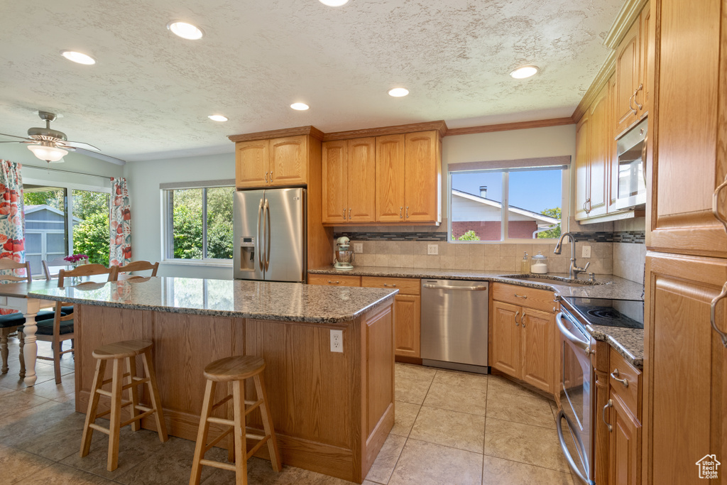 Kitchen featuring stainless steel appliances, a center island, a breakfast bar, tasteful backsplash, and recessed lighting