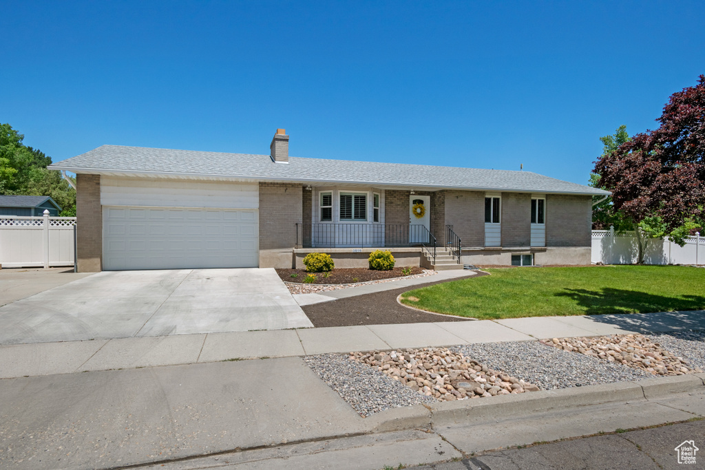 Ranch-style home with a garage, concrete driveway, brick siding, a chimney, and covered porch