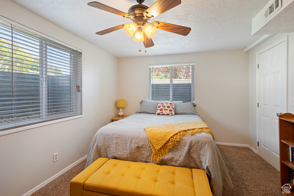 Carpeted bedroom with ceiling fan and a textured ceiling