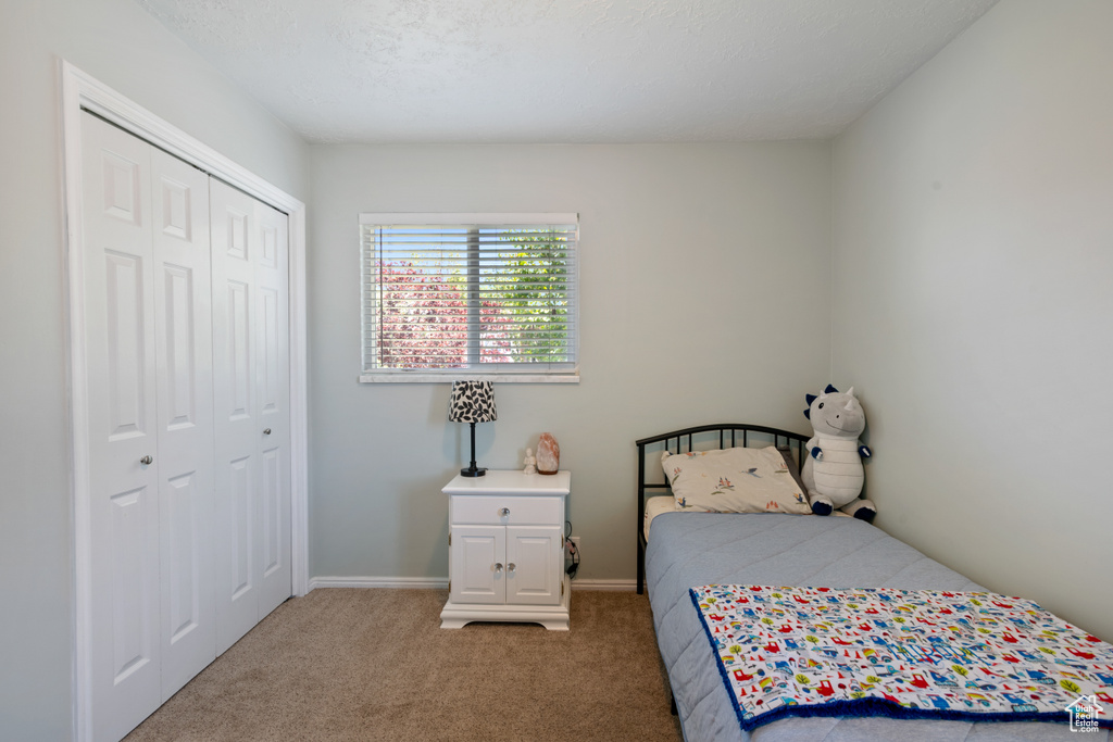 Carpeted bedroom featuring a closet and baseboards