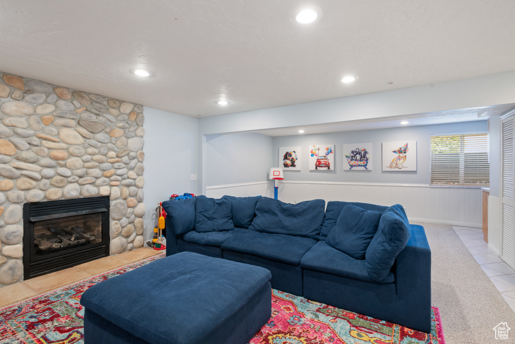 Carpeted living room featuring recessed lighting, a wainscoted wall, a fireplace, and tile patterned floors