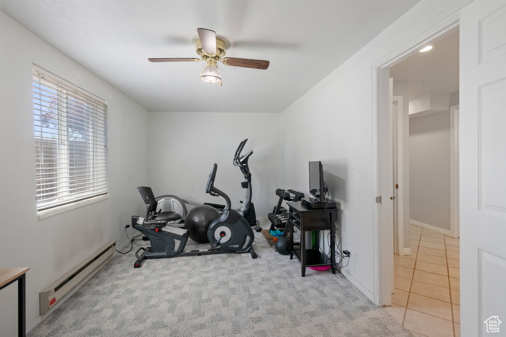 Exercise area featuring baseboard heating, ceiling fan, and carpet