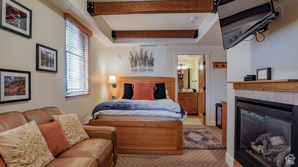 Bedroom with a glass covered fireplace, beamed ceiling, and connected bathroom