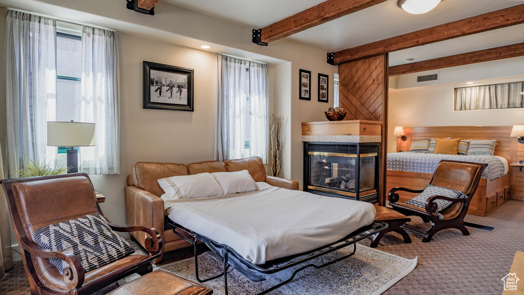 Carpeted bedroom with a fireplace and beam ceiling