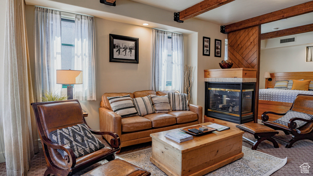 Living area featuring beam ceiling, a fireplace, and carpet floors