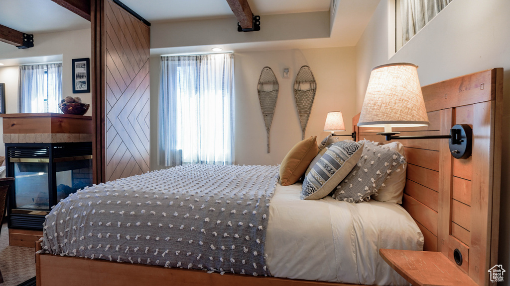 Bedroom featuring beamed ceiling and a multi sided fireplace