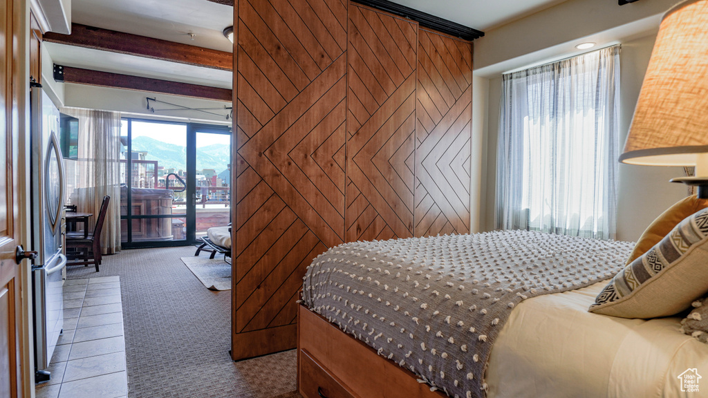 Bedroom featuring access to outside, carpet flooring, a city view, freestanding refrigerator, and beamed ceiling