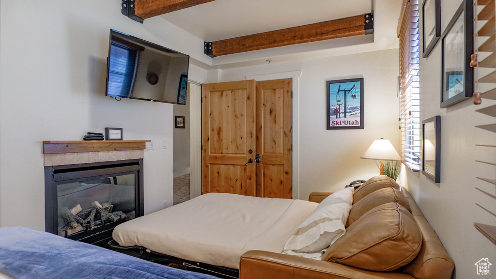 Bedroom featuring beamed ceiling and a glass covered fireplace