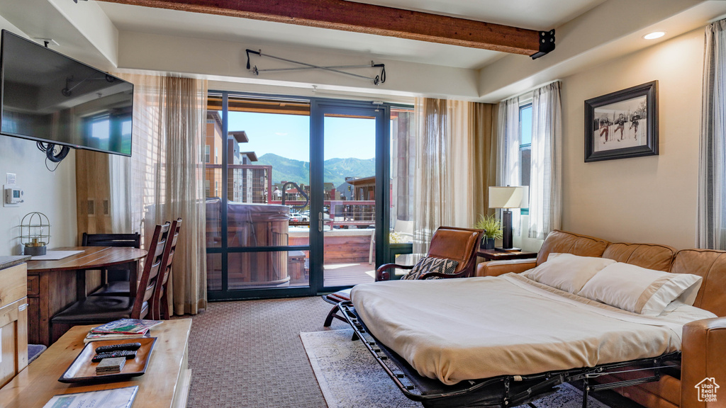 Bedroom with a mountain view, access to outside, carpet flooring, and beamed ceiling