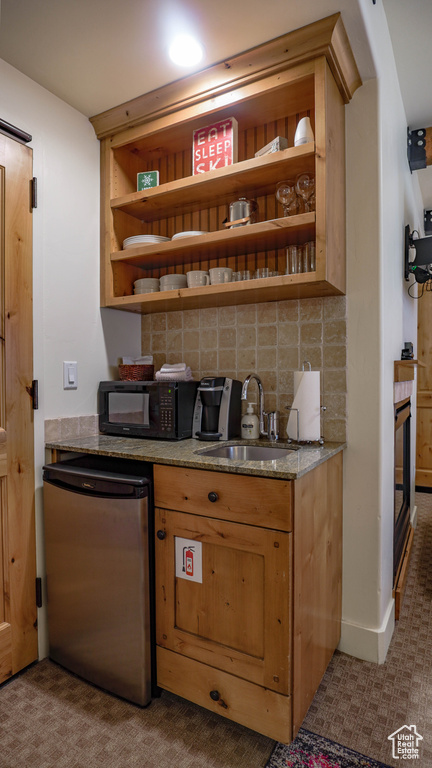 Bar with fridge, black microwave, and backsplash