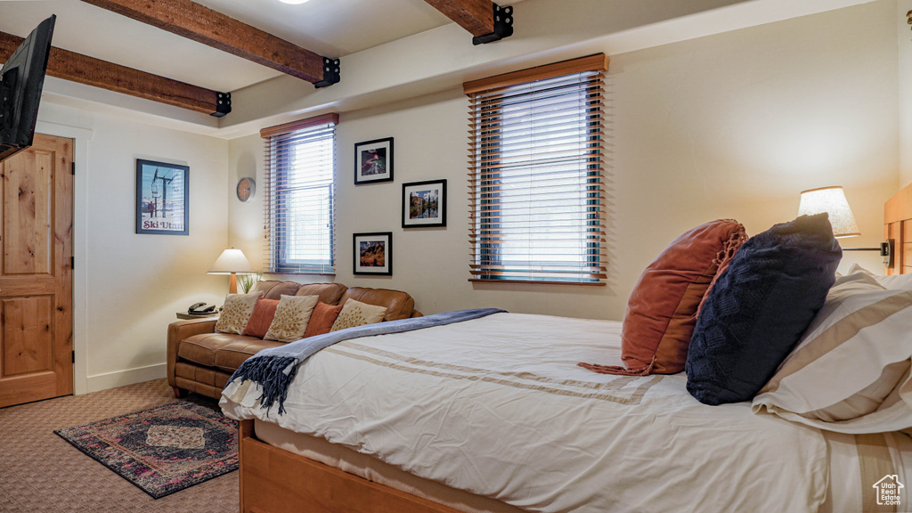 Carpeted bedroom with beamed ceiling and baseboards