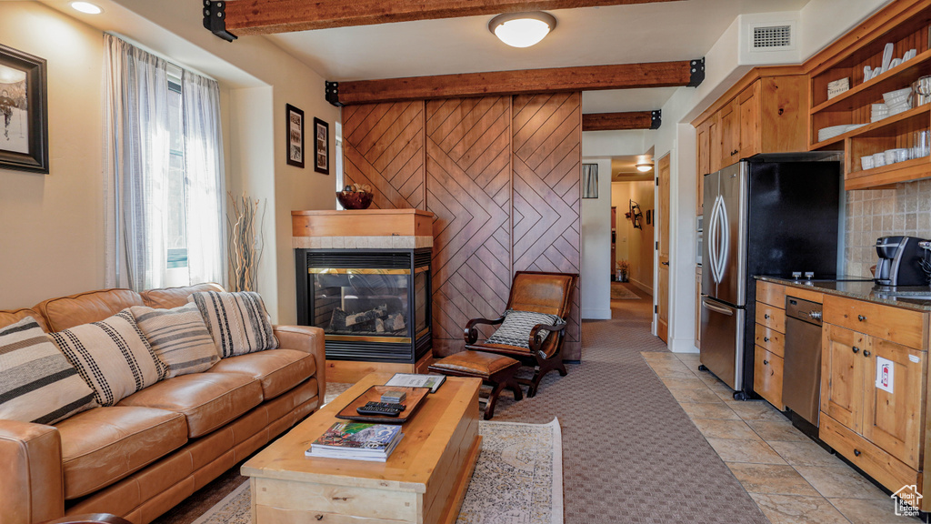 Living room with a multi sided fireplace, beamed ceiling, and light carpet