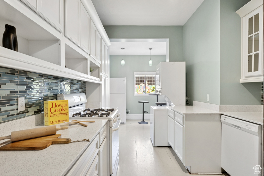 Kitchen with white appliances, backsplash, white cabinetry, open shelves, and glass insert cabinets