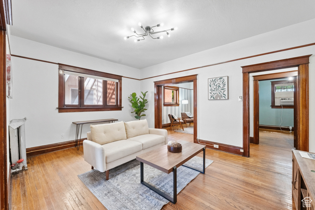 Living room with light wood-style flooring, a chandelier, and cooling unit