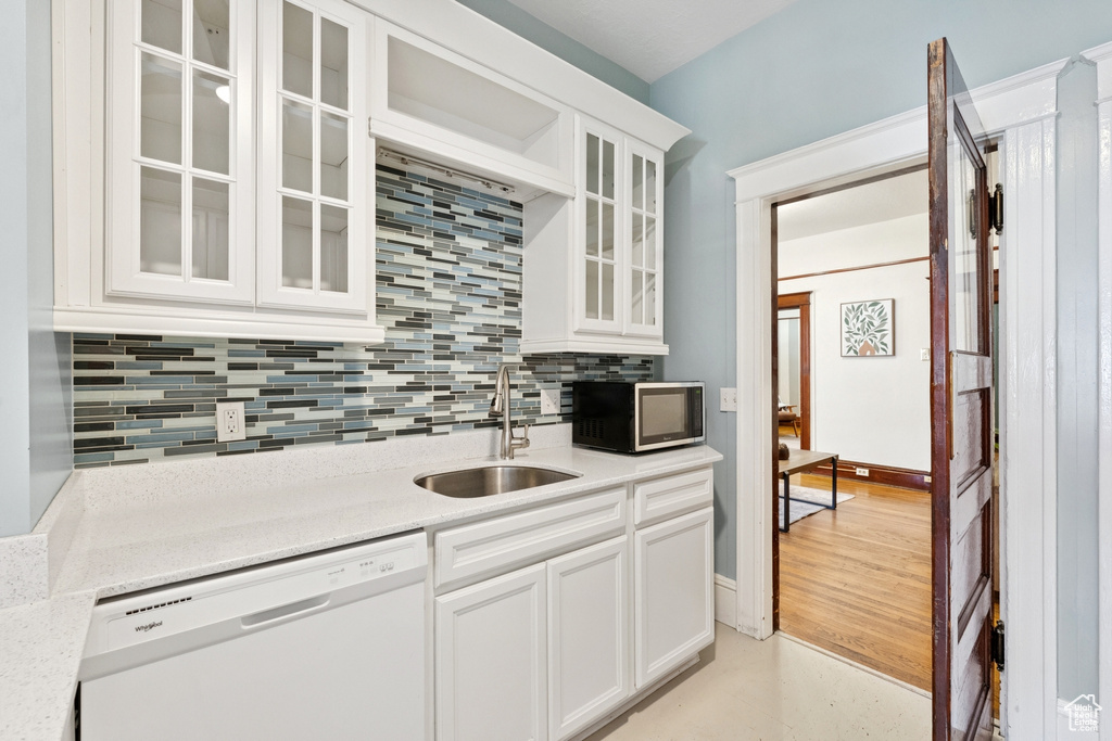Kitchen with dishwasher, decorative backsplash, glass insert cabinets, and white cabinets